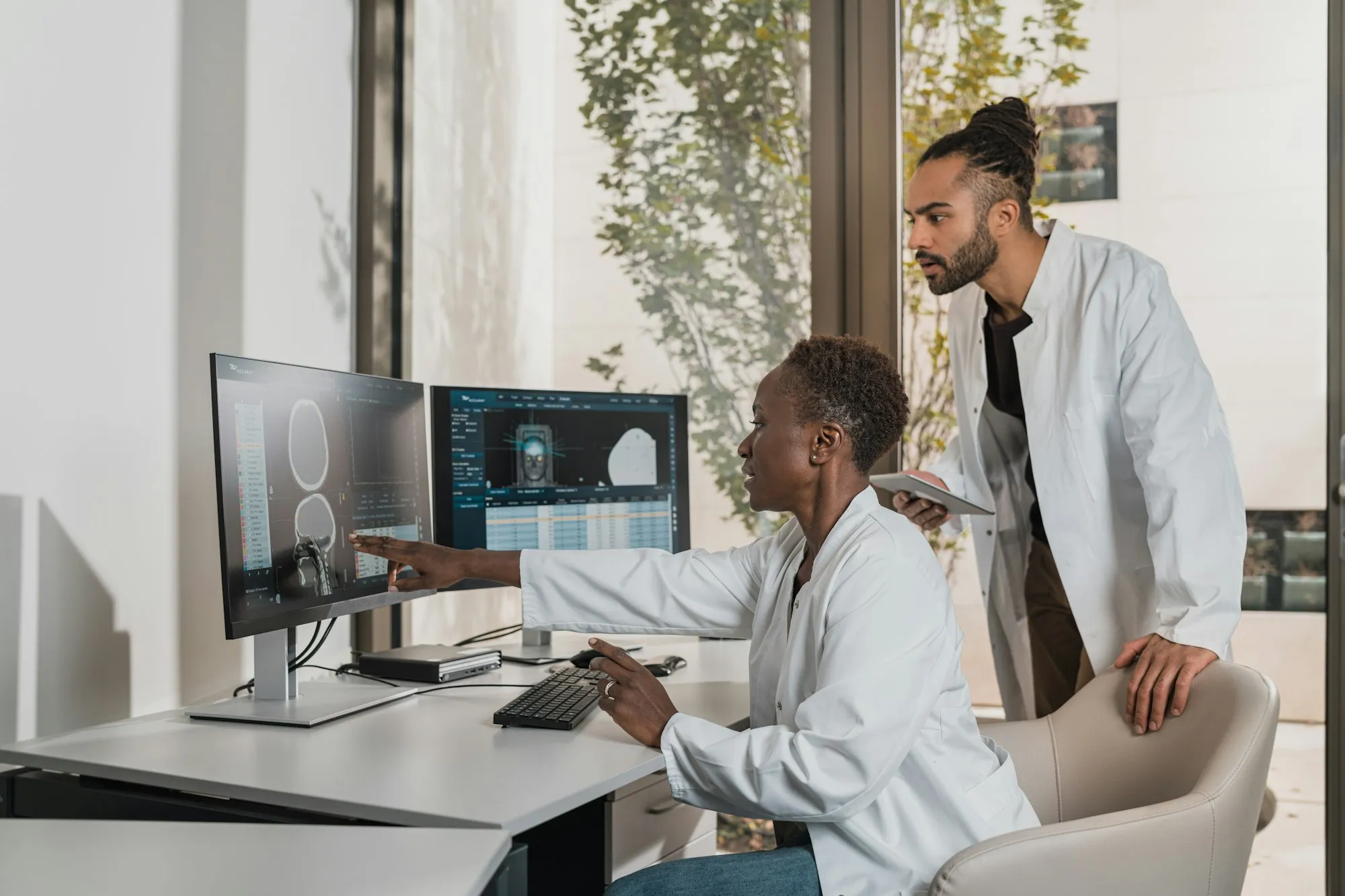 Two clinicians reviewing a scan on computer monitors