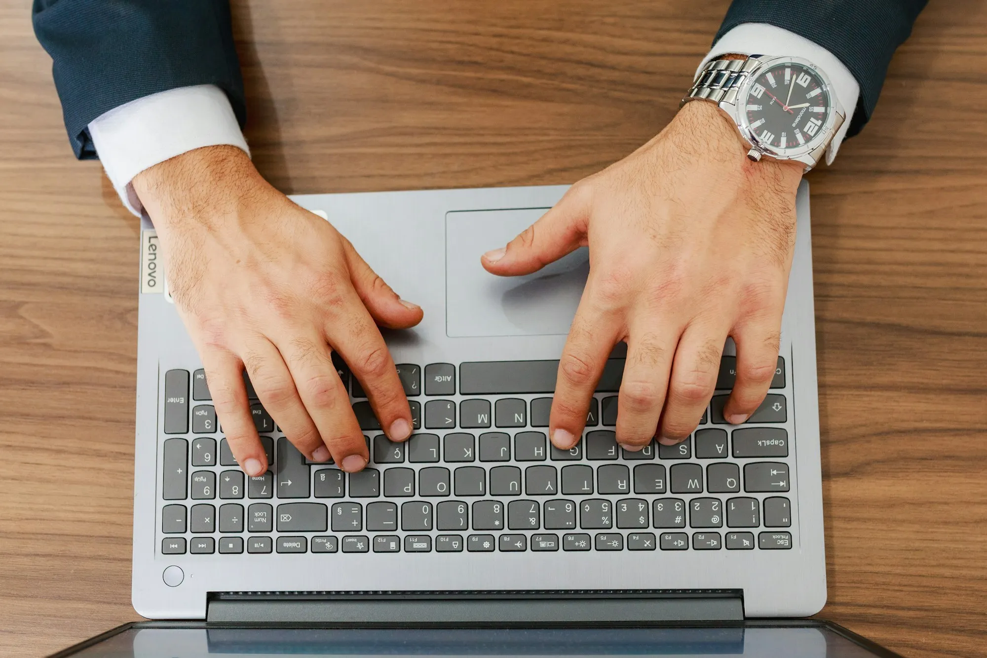 A person in a suit typing on a laptop at a desk