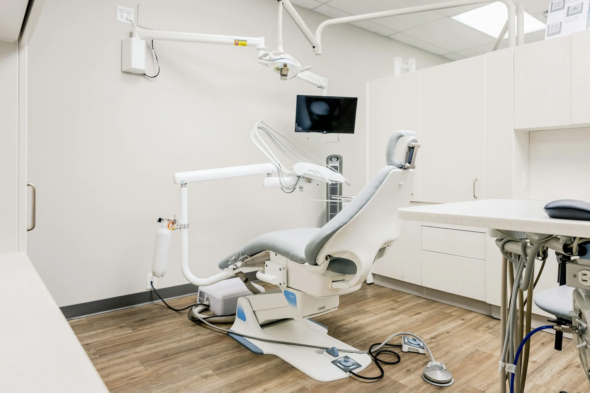 A dental operatory with a chair and a wall-mounted monitor