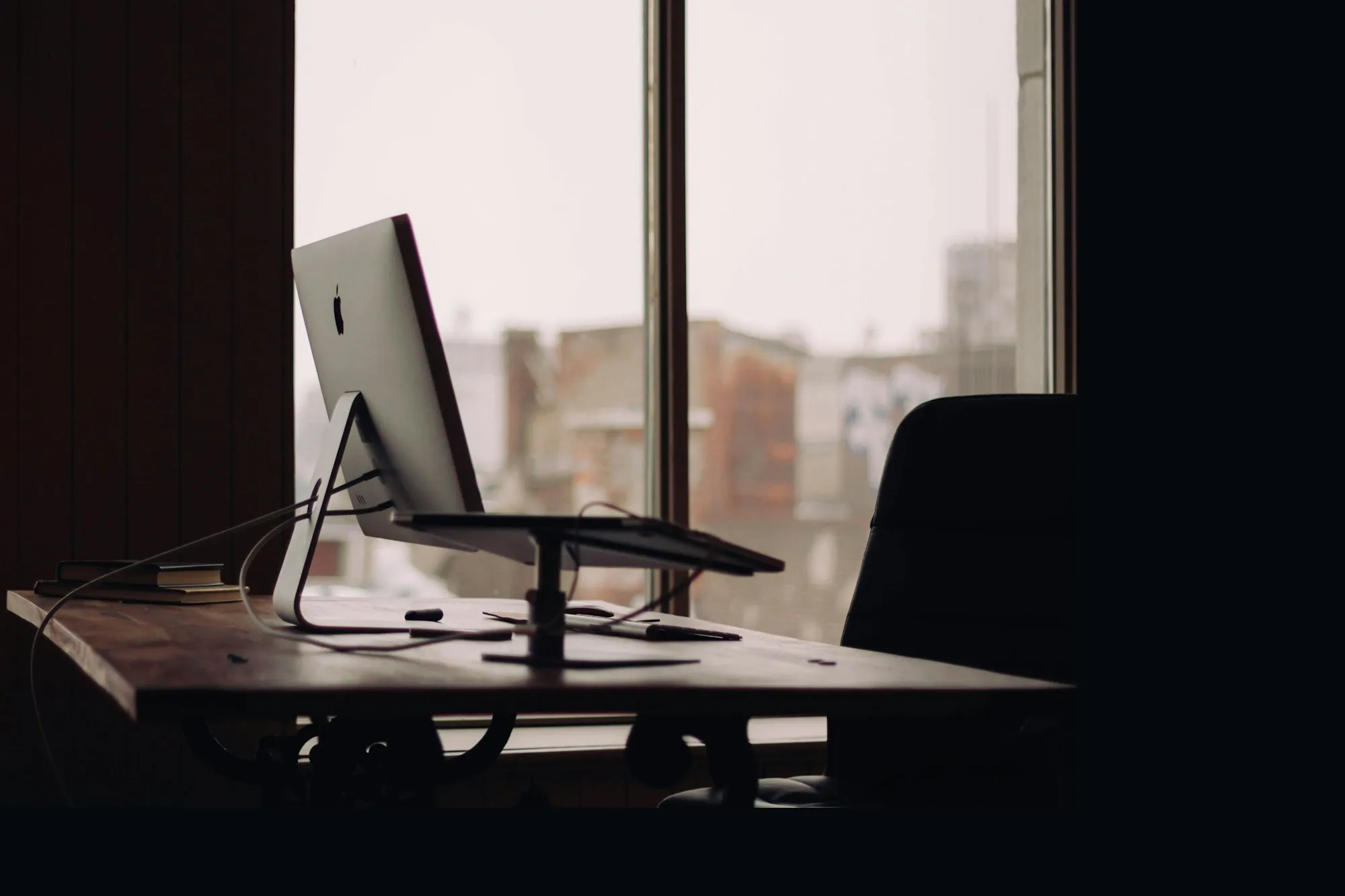 A computer on a desk in an office at dusk